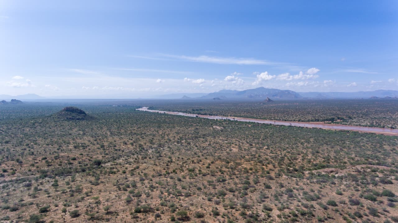 Wide aerial vista of arid and semi-arid rangelands with the Ewaso Ny'iro River as a distant ribbon